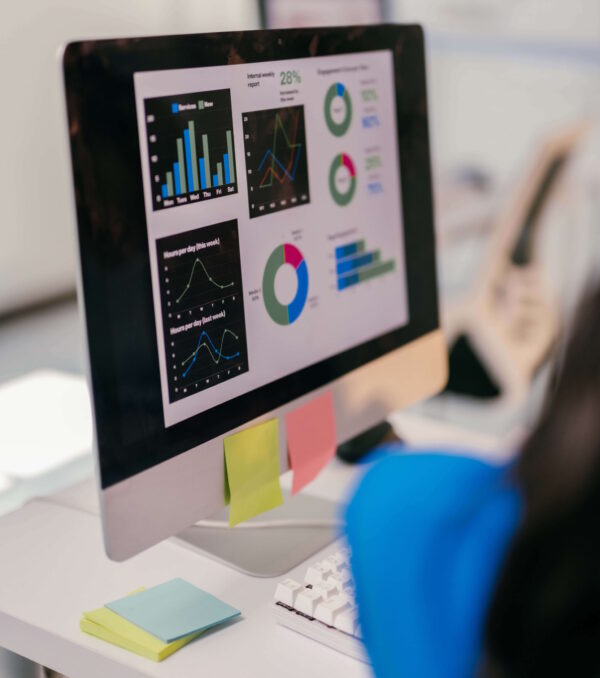 Focused businesswoman analyzes financial data on her computer, using graphs to plan for growth. Her cluttered desk shows her dedication to success