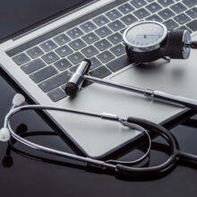close up view of stethoscope, tonometer, reflex hammer and laptop on glass surface
