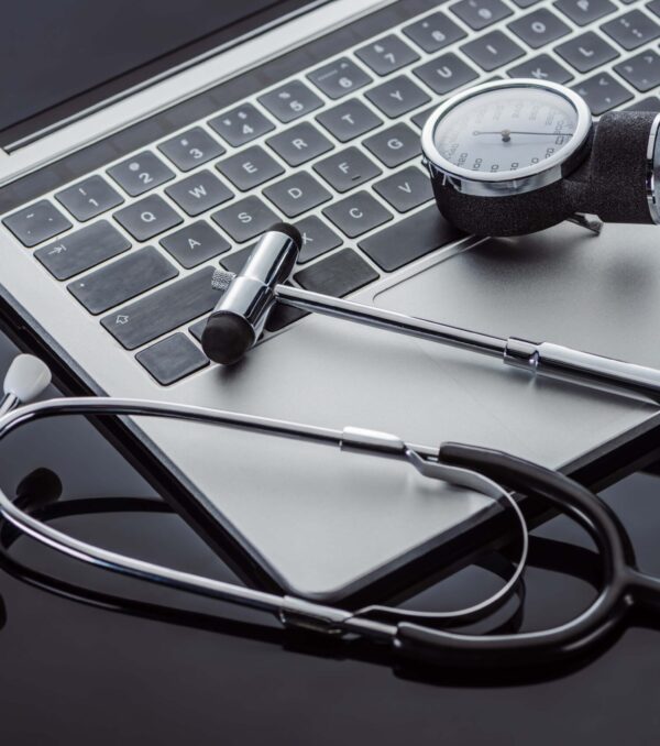 close up view of stethoscope, tonometer, reflex hammer and laptop on glass surface